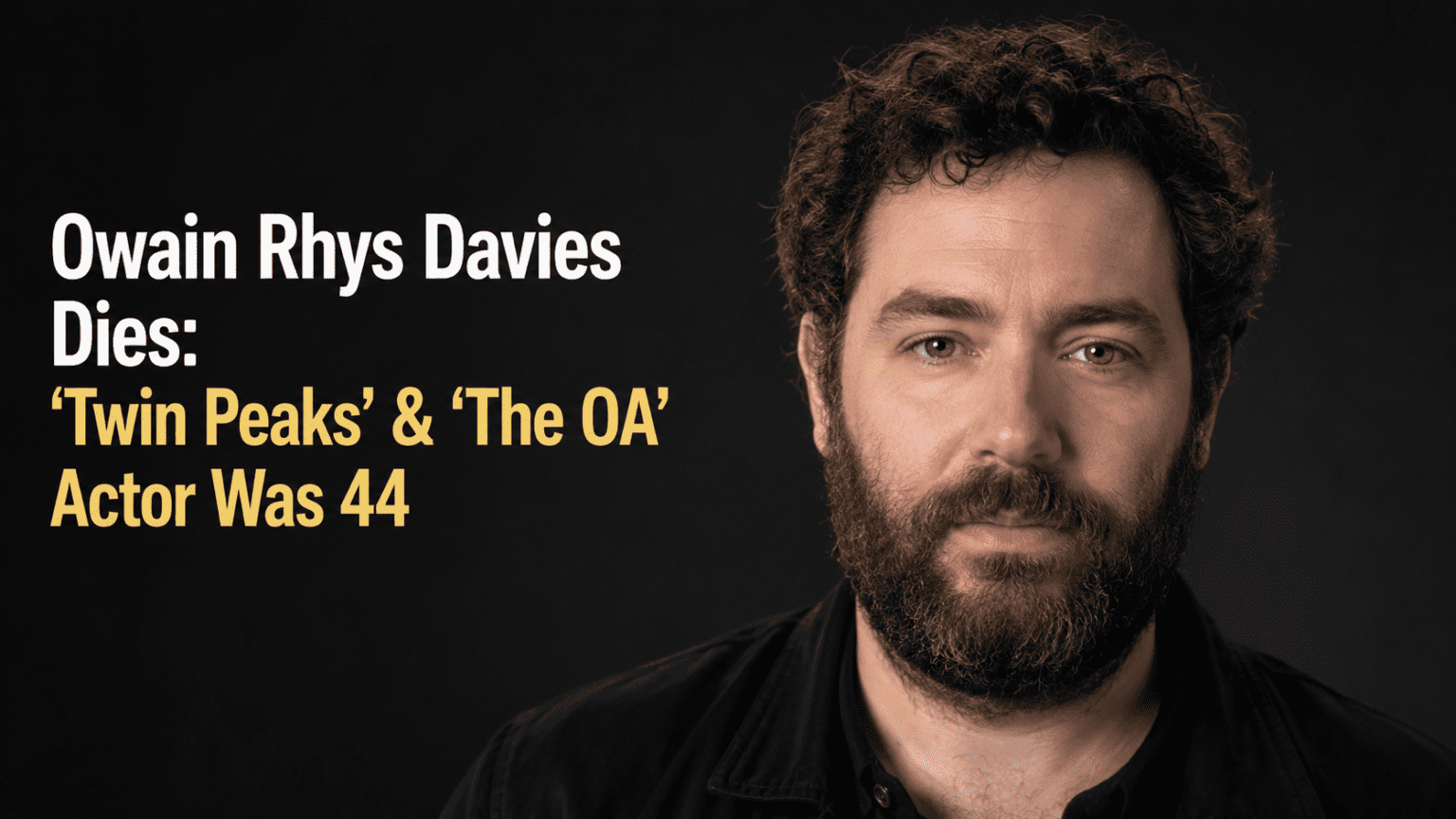 A clean, high-resolution 16:9 portrait photograph of Welsh actor Owain Rhys Davies on a red carpet. No text overlays, no infographics, and no AI-generated people.
