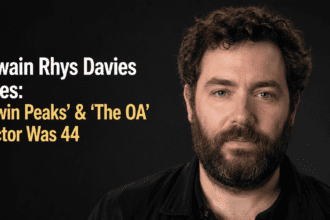 A clean, high-resolution 16:9 portrait photograph of Welsh actor Owain Rhys Davies on a red carpet. No text overlays, no infographics, and no AI-generated people.