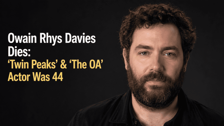 A clean, high-resolution 16:9 portrait photograph of Welsh actor Owain Rhys Davies on a red carpet. No text overlays, no infographics, and no AI-generated people.